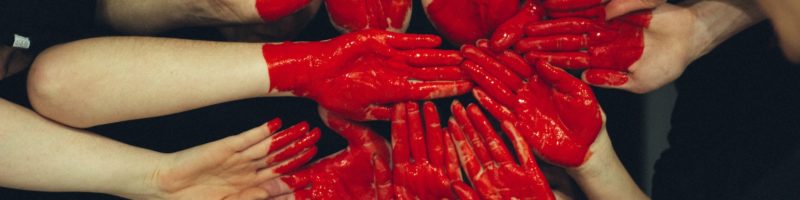 hands formed together with red heart paint
